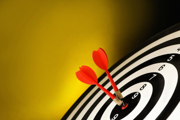 Red arrows hitting target on dart board against yellow background. Space for text