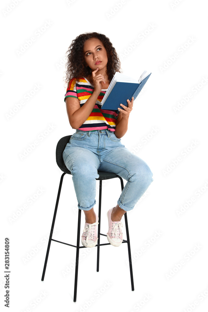 Wall mural Beautiful African-American woman reading book on white background