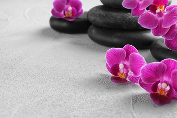 Orchid with spa stones on light grey background. Space for text