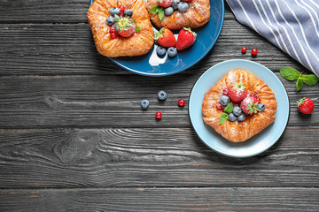 Fresh delicious puff pastry with sweet berries on dark wooden background, flat lay. Space for text