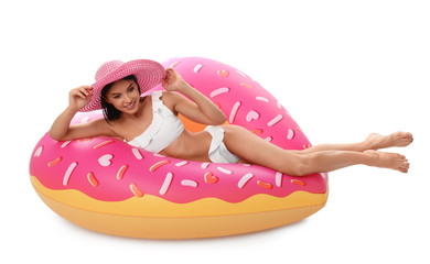 Beautiful young woman in stylish bikini with hat and inflatable ring on white background