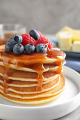 Delicious pancakes with fresh berries and syrup on table, closeup