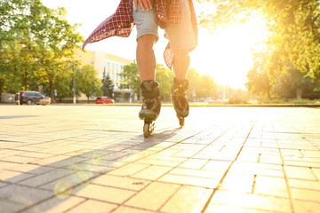 Young man roller skating outdoors on sunny day, closeup. Recreational activity