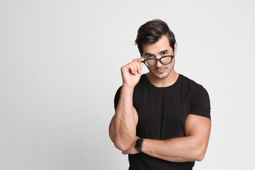 Portrait of handsome young man in black t-shirt with glasses on grey background. Space for text