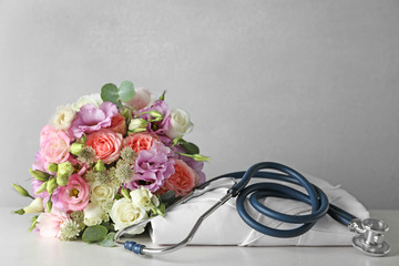 Composition with white medical robe and flowers on table, space for text. World health day