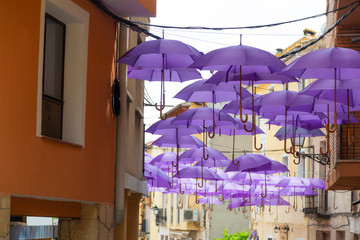 Fototapeta na wymiar Purple umbrellas hanged in main street in Brihuega, Guadalajara.