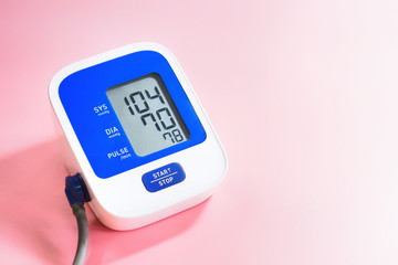 Health concept, blood pressure monitor on a pink background (Blood pressure measurement device is not specific to the brand)