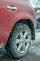 Fototapeta premium Car rear tyre in early winter season. Disk with a car tyre. Red car rear wheel.