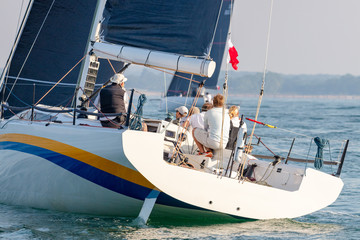 Obraz premium Rear View of Crew Abord a Sailing Yacht at Sea With coast Visible in Background