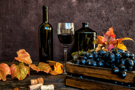 Red wine and grapes background. Wine and grapes in vintage setting with corks on wooden table. Toned image. Selective focus.