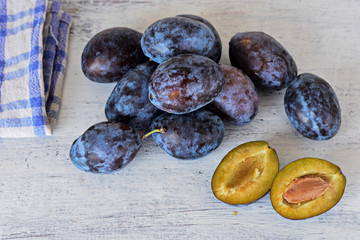 Fresh plums/ Harvested Fresh blue plums at light wooden background/ Food background/ Flatware