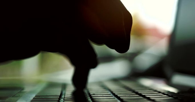 Silhouette of hands typing on computer keyboard, business man working on laptop pc in office