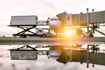 Ground handling of a white passenger airplane near the boarding bridge in the morning sun. Loading...