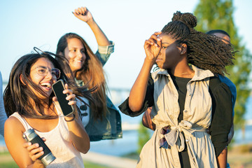 Smiling young women dancing and jumping together in park. Happy ladies listening music and dancing....