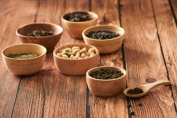 assortment of dry tea in white bowls on wooden surface