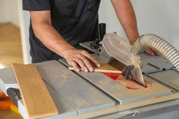 The worker cuts the parquet manually on a circular saw