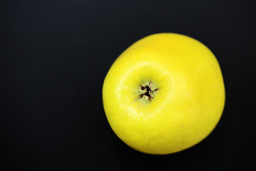 Ripe yellow apple on a dark background close-up