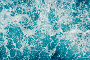 Fototapeta na wymiar Pale blue green sea surface with waves and foam, abstract background