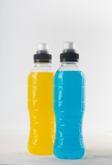 Isotonic energy drink. Bottles with blue and yellow transparent liquid, sport beverage on a white...