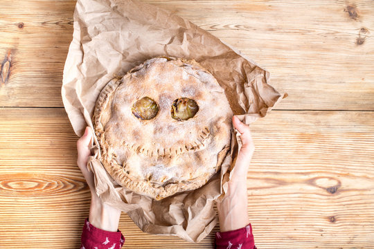 Funny  homemade pie for halloween in woman hands over wooden background
