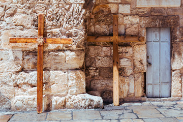 A steel door and two big christian wooden crosses lean against stone wall of the Church of the Holy...