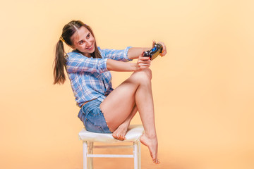 Girl playing computer games with a joystick on a yellow background