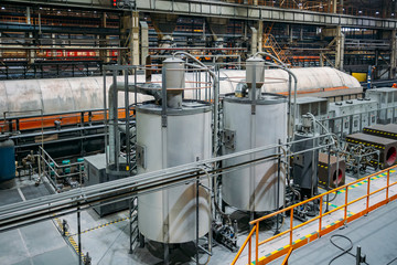 Steel tanks connected by pipelines in factory workshop 