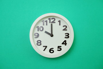 White round clock showing Ten o'clock on green background