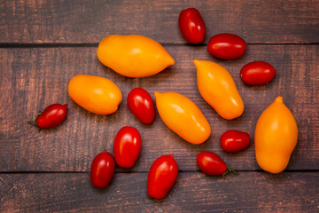yellow and red tomatoes of different shapes and sizes on a rustic table.