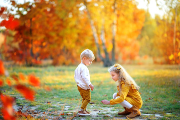 Cute children are walking in a beautiful autumn park at sunset.