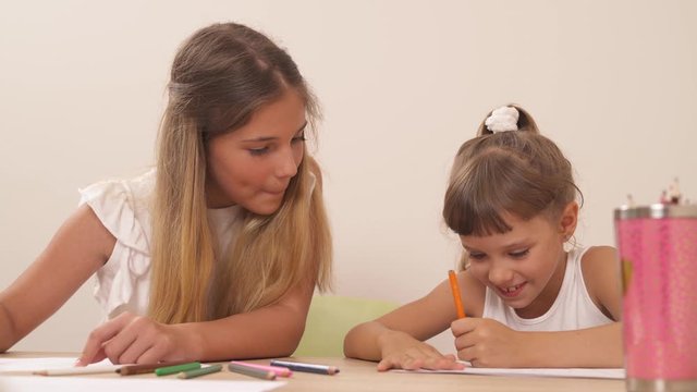 Teenage girl talking to her little sister while drawing during psychological session. Family psychology