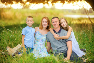 Fototapeta premium portrait of a happy family outdoors, sitting together on the grass and hugging