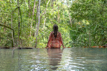 Young woman near turquoise water of cascade waterfall at tropical rain forest, island Koh Phangan, Thailand