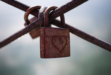 Zwei rostige Vorh&auml;ngeschl&ouml;sser an Br&uuml;cke mit Herz Gravur