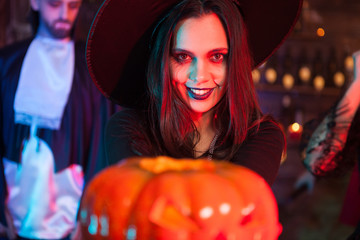 Sexy witch holding a magic pumpking with a scary expression for halloween party