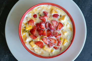 Mango, passion fruit, strawberry and yogurt brulee. Fruit dessert on breakfast with wedges of perfectly ripe in season mangoes and strawberry, covered fresh passion fruit pulp