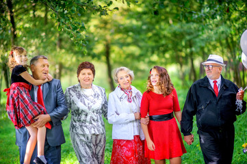 portrait of a big happy family in the park, grandparents celebrate birthday together with grandchildren