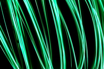 Long exposure, light painting photography.  Vibrant abstract streaks of neon green color against a...