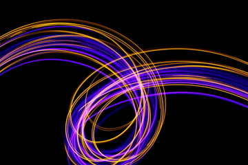 Long exposure, light painting photography.  Vibrant abstract streaks of neon pink and gold color against a black background.