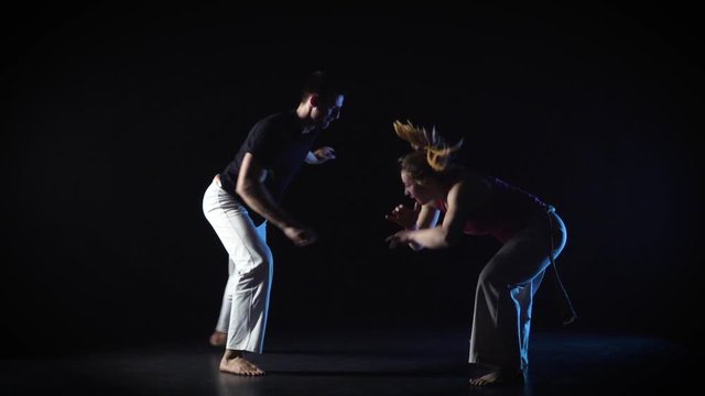 Man and woman performing complex of martial art of capoeira. Slow motion.