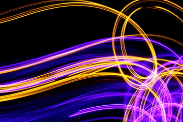 Long exposure, light painting photography.  Vibrant abstract streaks of neon pink and gold color against a black background.