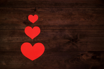 Red paper hearts on wooden table.