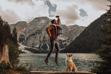 A man with his dog works on the phone on Lake Braies