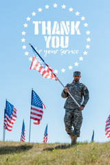 handsome soldier in military uniform and cap holding american flag with thank you for your service...