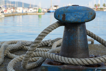 Fototapeta na wymiar bollard from iron with a ship rope at the pier on the port