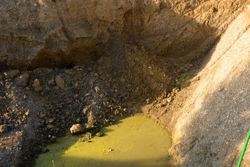 earthmoving works at excavation site, new excavated excavation pit with groundwater at sunrise