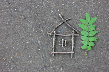  miniature house made of branches on the asphalt near a green leaf