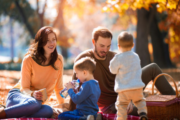Happy family of four having fun together in the park in autumn