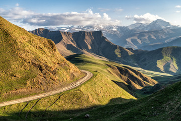 Mountain valley shined with the sunset sun with the road on an abrupt slope © Sergei