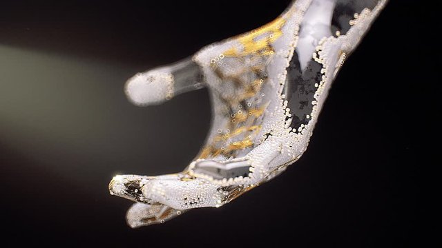 Stock motion graphics video shows tiny particles covering a glass hand as it moves on a black background